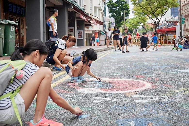 People doodling on the road at the "Walk the Chalk" event in Telok Ayer Street during Car-Free Sunday SG in May. This weekend, visitors can try manoeuvring a pedal go-kart around Telok Ayer and the Central Business District.