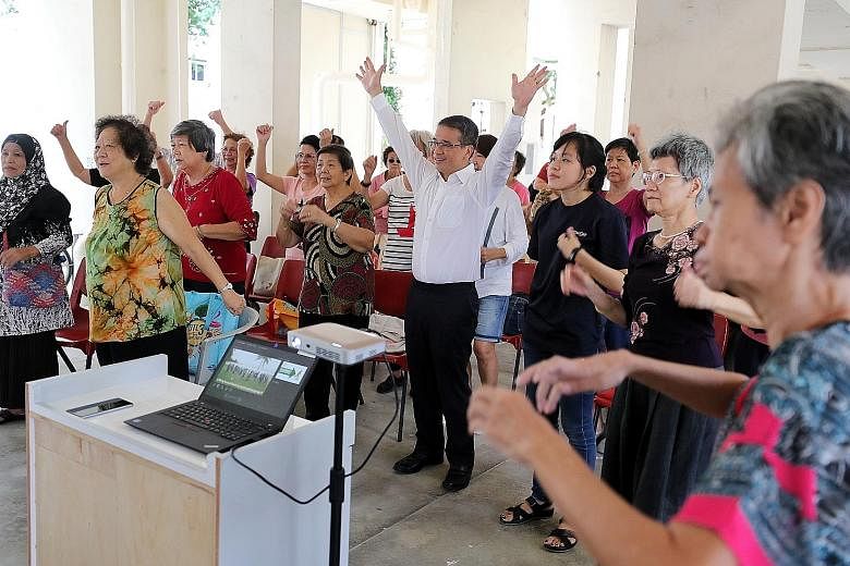 Senior Minister of State for Health Edwin Tong taking part in a workout with seniors and caregivers during a "Happy Kopitiam" session at Kaki Bukit Ville Residents' Committee Centre yesterday. The sessions, organised by Montfort Care, aim to help par