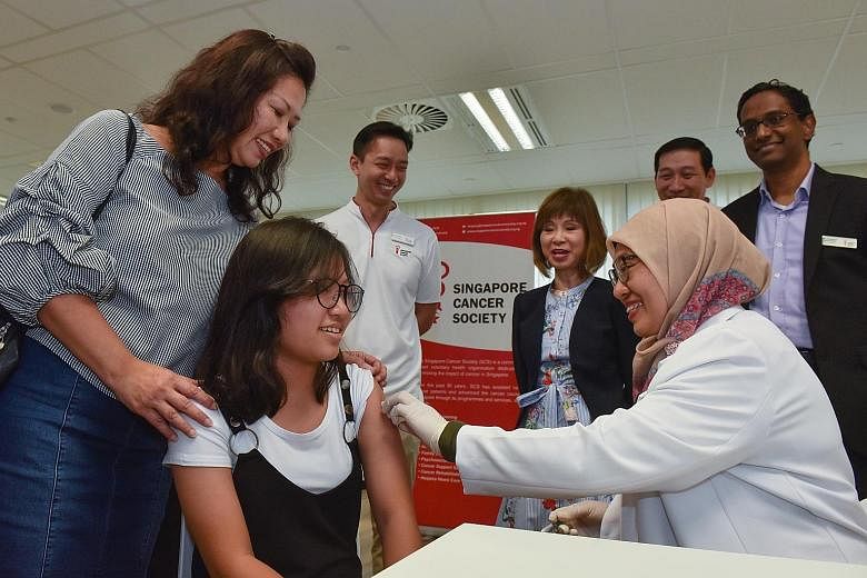Chloee Lee receiving her HPV vaccination yesterday from Dr Hafidza Mohd Said, with encouragement from her mother, Madam Dianna Tan. Behind them are (from left): Mr Melvin Seet, senior manager of community health, Singapore Cancer Society (SCS); Dr Am