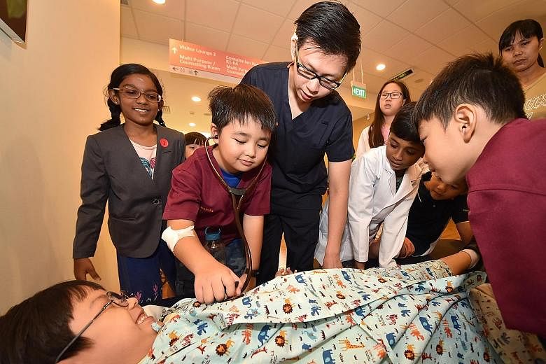Dr Wong Wen Kai teaching children how to use medical instruments at Alexandra Hospital's open house yesterday.