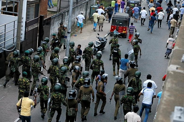 Members of Sri Lanka's Special Task Force and the police chasing away supporters of the country's newly-appointed Prime Minister Mahinda Rajapaksa after a security guard of sacked petroleum minister Arjuna Ranatunga shot and wounded three people in f