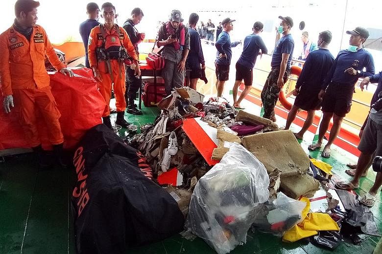 Indonesian rescuers with some items recovered yesterday from the crash site, including personal belongings and pieces of the wreckage, as well as a body. So far, rescuers have sent 34 body bags containing human remains for DNA testing.