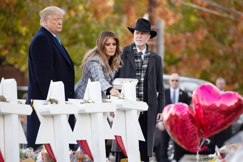 Mrs Melania Trump, with Mr Donald Trump (left) and Rabbi Jeffrey Myers, placing a flower at a memorial at the synagogue.