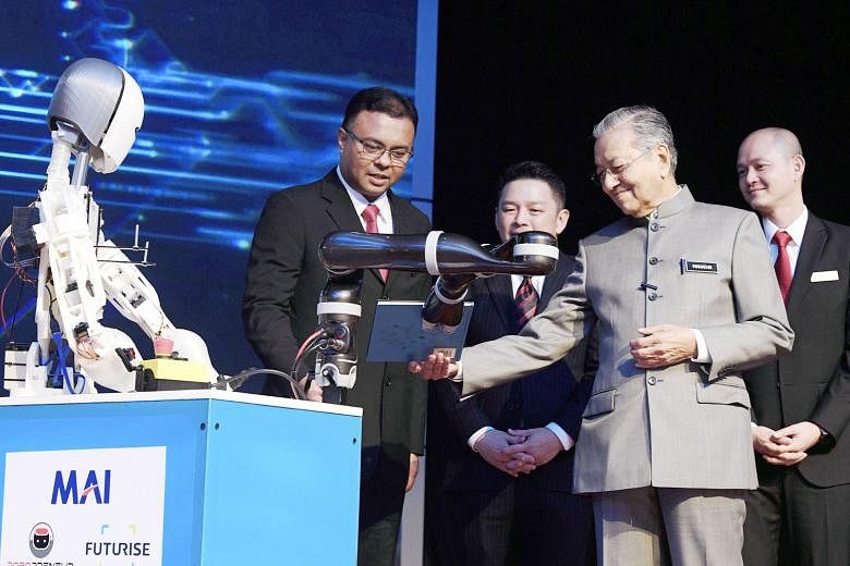 Tun Dr Mahathir Mohamad receiving the National Policy on Industry 4.0 book from a robotic arm at the launch event yesterday. With him are International Trade and Industry Minister Darell Leiking (third from right) and Deputy Minister Ong Kian Ming (r