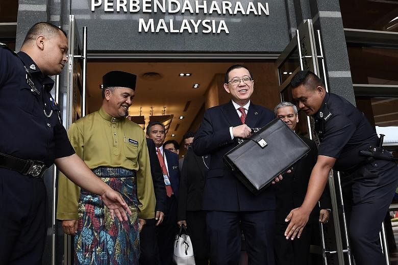 Finance Minister Lim Guan Eng carrying a bag containing his budget speech on his way to Parliament in Kuala Lumpur yesterday. With him were Deputy Finance Minister Amiruddin Hamzah (left) and Treasury Secretary-General Ahmad Badri Mohd Zahir (right, 