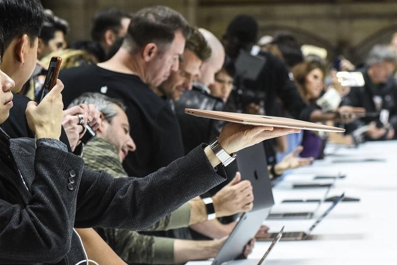 People getting a feel of new Apple products during a launch event in the Brooklyn borough of New York City on Tuesday. Apple on Thursday said it would stop reporting unit sales data for its iPhone, iPad and Mac computer products.
