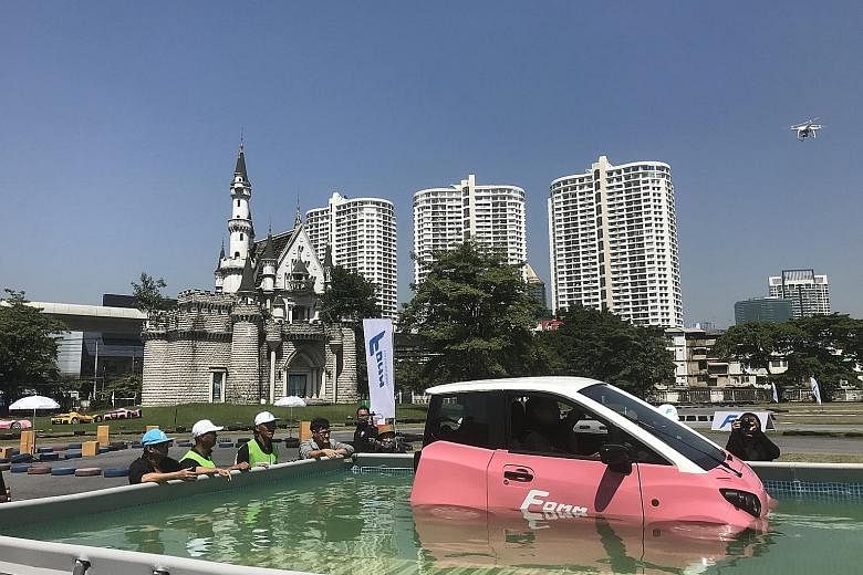 The FOMM One car floating in a 1.2m-deep pool of water. The watertight battery-powered vehicle is designed to help owners survive floods and transport them to the nearest dry ground.
