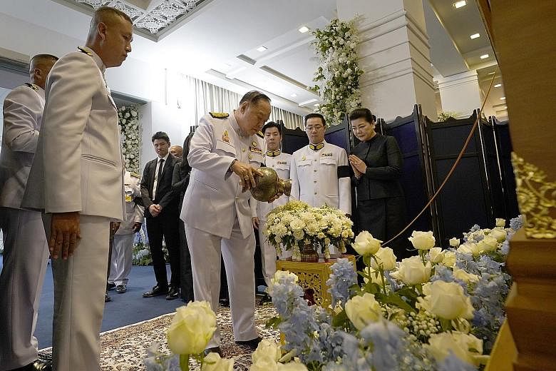 Thai Deputy Prime Minister Prawit Wongsuwan pouring holy water during the funeral ceremony of Mr Vichai Srivaddhanaprabha (above) at Wat Thepsirin, a temple in Bangkok, yesterday. Watching on were the late Mr Vichai's wife Aimon and son Aiyawatt (in 
