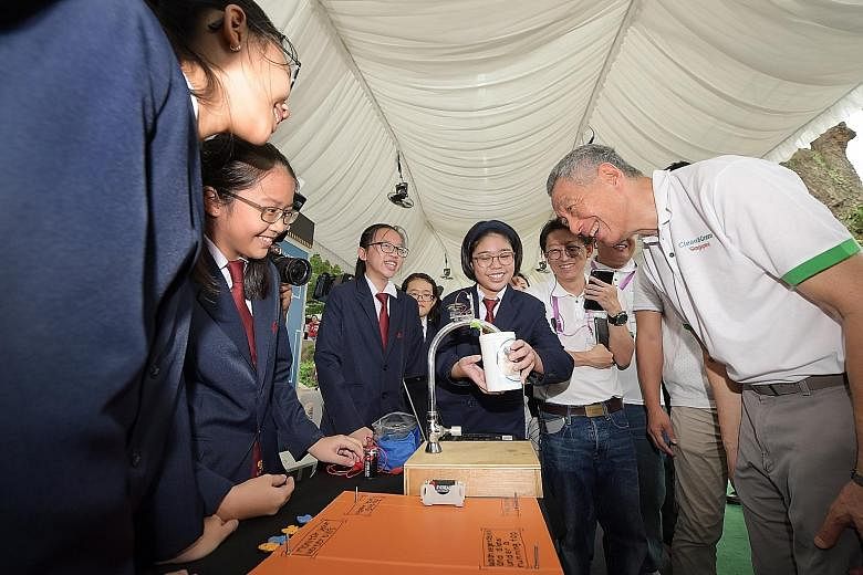 Students from Nan Chiau High School showing Prime Minister Lee Hsien Loong their project, which uses a water sensor installed at the tap to help users save water, at the Clean and Green Singapore carnival at Wisma Geylang Serai yesterday.