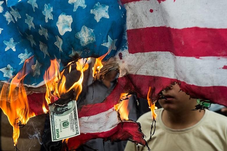 Protesters burning the US flag and a US$100 note during a demonstration on the anniversary of the US embassy seizure in Teheran on Sunday.