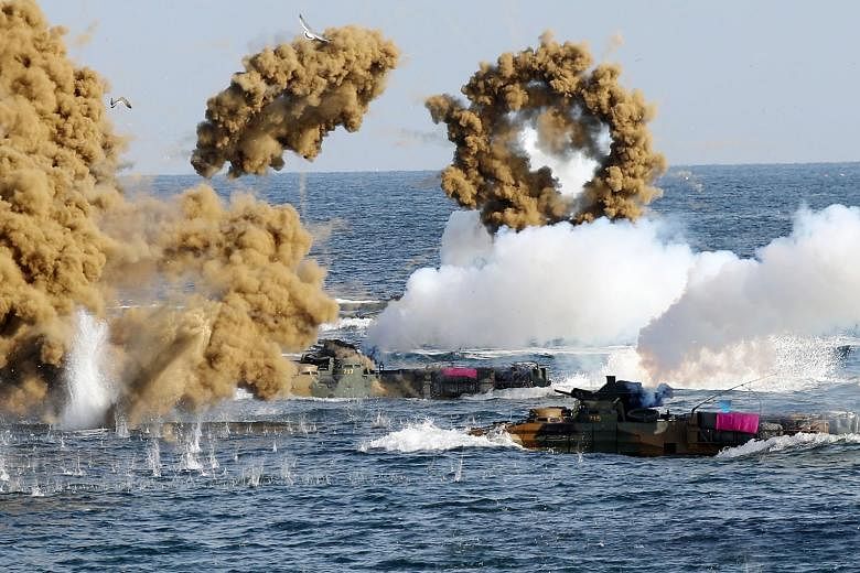 South Korean Marine amphibious assault vehicles firing smoke shells on the seashore in a landing operation in the southern city of Pohang yesterday, during an exercise with the US military.