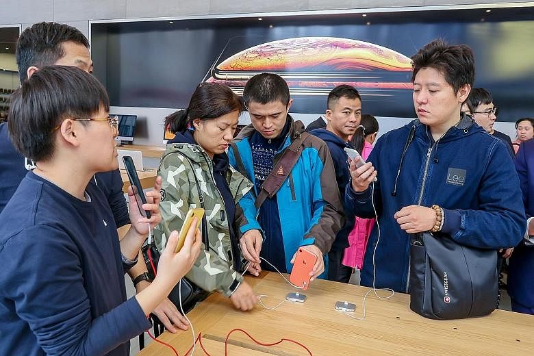 Potential buyers of the iPhone XR at an Apple store in Shanghai. Companies that supply Apple have been badly hit after a Nikkei business report said the tech firm had told Taiwan's Foxconn and Pegatron to scrap planned new production lines for the iP
