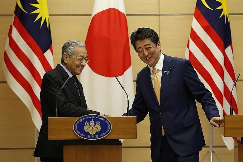 Malaysian Prime Minister Mahathir Mohamad exchanging greetings with Japanese Premier Shinzo Abe at the end of their joint news conference at Mr Abe's official residence in Tokyo yesterday.