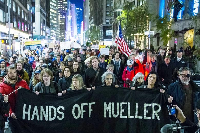 People marching through Times Square in New York City on Thursday night, a day after President Donald Trump forced the resignation of Attorney-General Jeff Sessions. The move has cast doubt on the fate of special counsel Robert Mueller's Russia inves