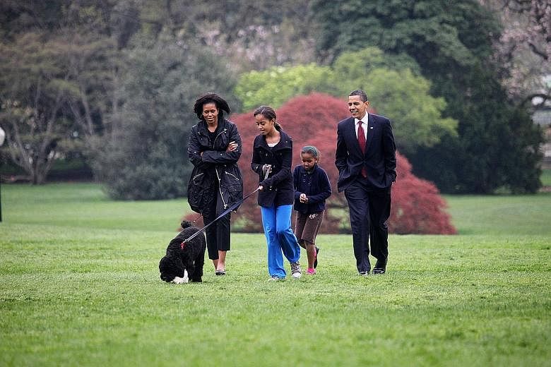 Above: Then US First Lady Michelle Obama, then President Barack Obama and their children, Malia and Sasha, with their dog Bo at the White House in 2009. In her book, Mrs Obama writes of how fertility treatments allowed her to conceive her daughters. 