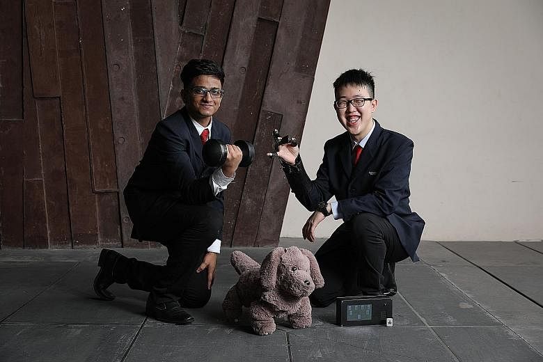Republic Polytechnic's Azimah and Jordan Sia with their invention - a locked pill dispenser that helps patients keep track of the medication they take daily. Ms Heng Yin Qi and Mr Lee Wei Juin from SP with Shaky - a device that can be attached to obj
