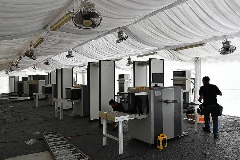 Security personnel setting up X-ray machines and walk-through metal detectors near Suntec Singapore International Convention and Exhibition Centre, the summit venue, yesterday. The area around the venue has been declared an enhanced-security special 