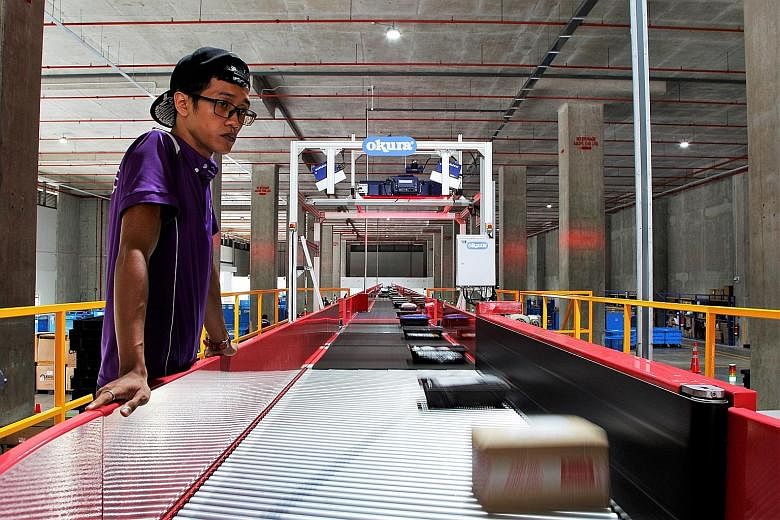 A Qxpress staff monitoring Qoo10 parcels on the conveyor belt to ensure that they are right-side up for scanning. These parcels can now be collected at 7-Eleven stores as well as the nationwide common parcel locker system.