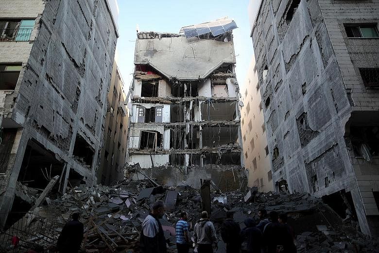 Palestinians gathering near the remains of a building that was completely destroyed by an Israeli air strike in Gaza. The fighting began after Israeli intelligence operatives inside the Gaza Strip were challenged by Hamas fighters.