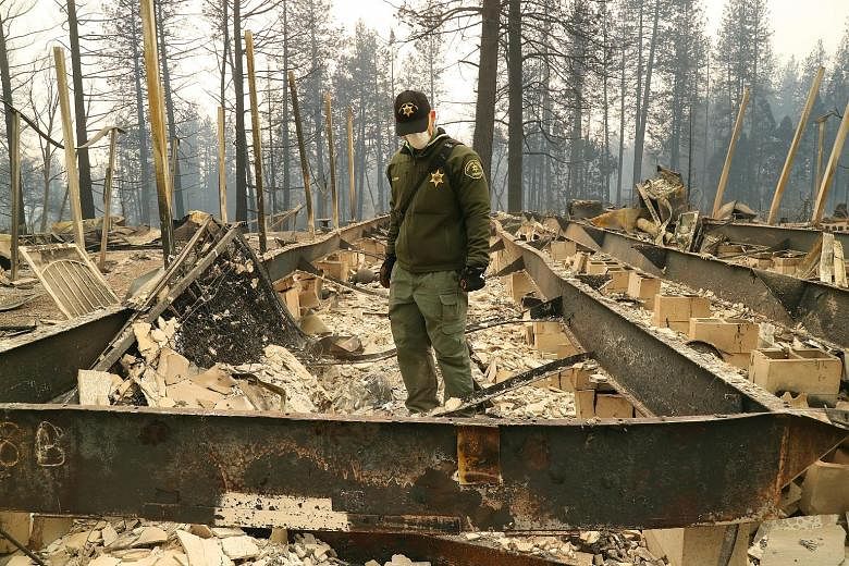 An investigator from the Fresno County Sheriff's Department searching the remains of a home at Ridgewood Mobile Home Park on Monday, in the aftermath of the Camp Fire blaze in Paradise, California.