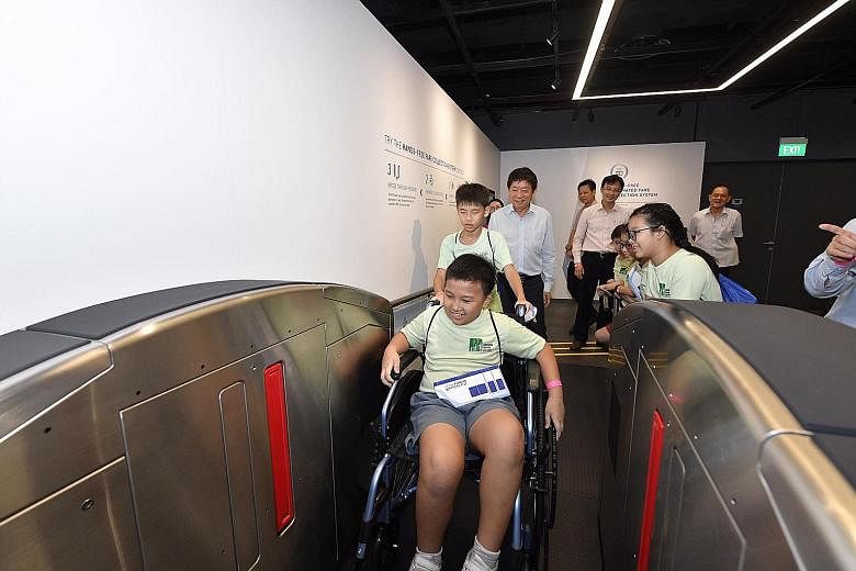 Ten-year-old Parry Tan getting a first-hand experience of how wheelchair users can use hands-free MRT station fare gates yesterday. He was among some 30 visitors to the Singapore Mobility Gallery at the Land Transport Authority's headquarters in Hamp