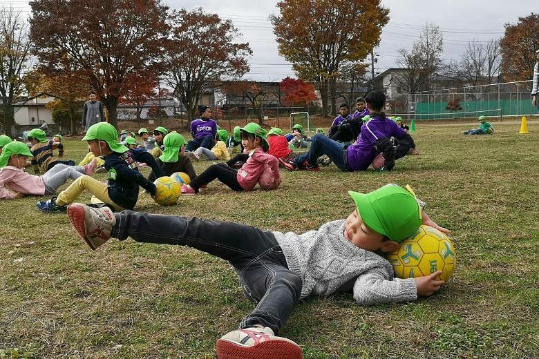 A Japanese boy stretching with a ball during a clinic arranged by J2 football club Matsumoto Yamaga with the Matsumoto City Kiri Kindergarten. Some 120 children from the kindergarten spent two hours with four Singaporeans and coaches from Yamaga, kic