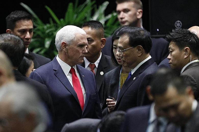 Above: US Vice-President Mike Pence and Chinese Premier Li Keqiang speaking to each other at the 13th East Asia Summit (EAS) yesterday. The US and China are in the midst of a trade war. Below: Russian President Vladimir Putin (left) speaking with Mr 