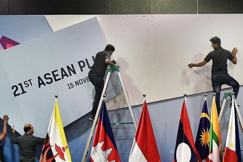 In between sessions at the Asean Summit, staff work to change the signage at the Suntec Singapore Convention and Exhibition Centre.