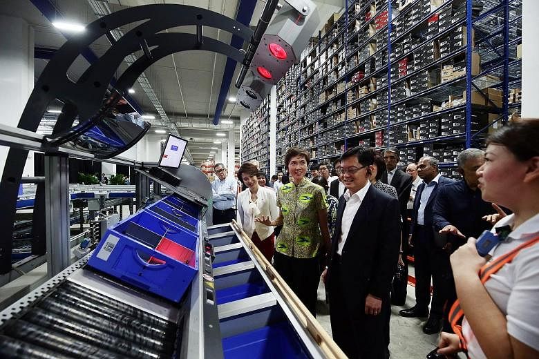 Finance Minister Heng Swee Keat (foreground), who chairs the Future Economy Council, with fellow council members, including Manpower Minister Josephine Teo and Senior Parliamentary Secretary Low Yen Ling, on a tour of the SingPost Regional eCommerce 