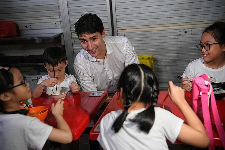 Canadian Prime Minister Justin Trudeau chatting with Ms Brenda Lim's children (from left) Rizuan, six, Long Jun, four, Zai Men, eight, and Yue Zuan, nine, during an early morning visit to Adam Road Food Centre yesterday.