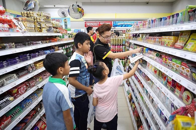 Cheers area manager Ricky Tan, 34, helping beneficiaries of the fund shop at a Cheers convenience store. Each child was given $20 to buy whatever he or she wanted.