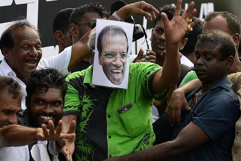 A supporter of Sri Lanka's ousted prime minister, Mr Ranil Wickremesinghe, wearing a mask depicting Sri Lankan President Maithripala Sirisena (left), during a rally in Colombo on Thursday. It was also chaos in Parliament as protesting government memb