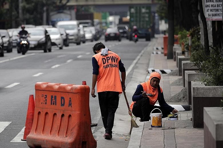 Workers yesterday painting a pavement in preparation for the state visit of Chinese President Xi Jinping. Philippine and Chinese officials are working to close at least two infrastructure deals during Mr Xi's visit.