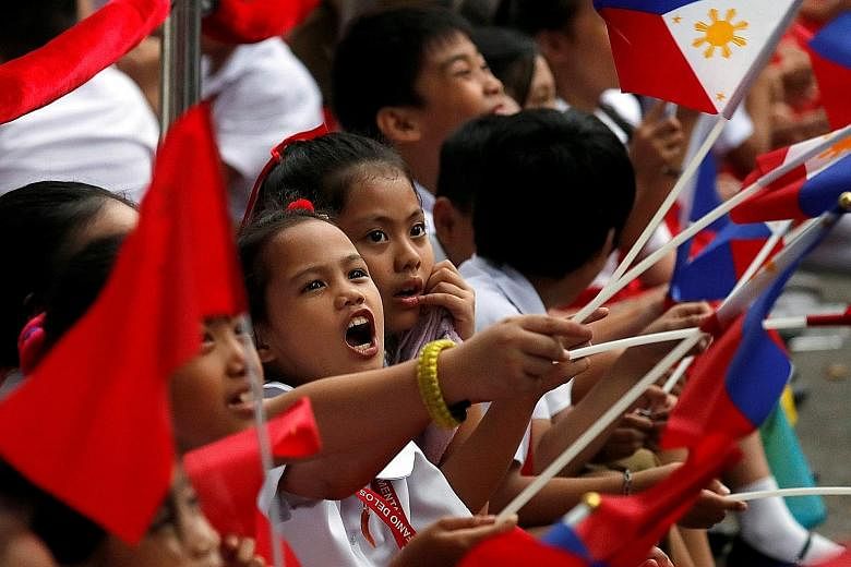 Schoolchildren waving the Philippine and Chinese national flags as they waited for the convoy of visiting Chinese President Xi Jinping near the Malacanang Presidential Palace in Manila yesterday. A Filipino protester making his views felt during a pr