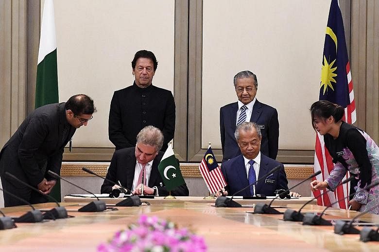 Mr Khan and Dr Mahathir looking on as Pakistani Foreign Minister Shah Mehmood Qureshi and Malaysian Home Minister Muhyiddin Yassin signed documents during a ceremony yesterday.