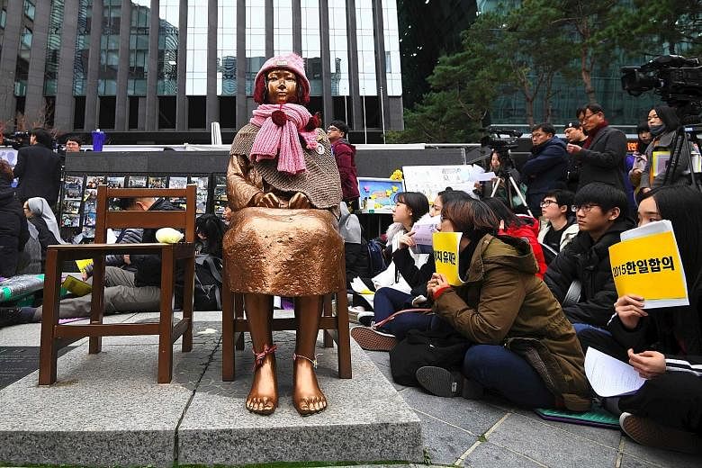 South Korean protesters at a statue of comfort women in Seoul yesterday. Historians estimate that up to 200,000 Korean women were forced to become sex slaves for the Japanese military during World War II. There is pressure on Seoul to revoke its 2015