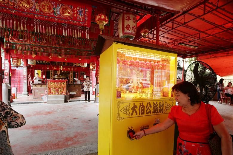 Devotee Teo Mui Kheng, 63, using the 4-D vending machine at the Goh Chor Tua Pek Kong temple. All she has to do is put money into the vending machine which, in return, will spit out a card with 4-D numbers.