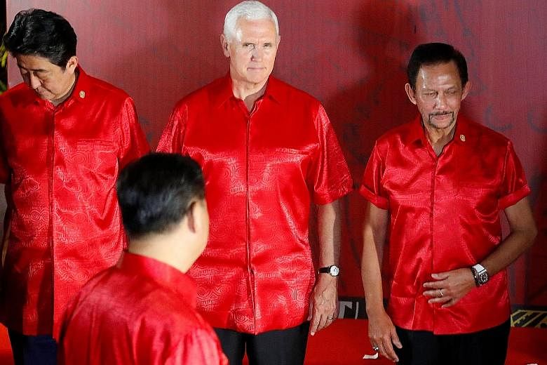 US Vice-President Mike Pence, flanked by Japan's Prime Minister Shinzo Abe (left) and Brunei's Sultan Hassanal Bolkiah, faces Chinese President Xi Jinping (back to camera) as they prepare for a group photo at a gala dinner during the Apec summit in P
