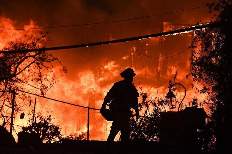 A firefighter outside a burning home during the Woolsey Fire in Malibu, California, early this month. The latest edition of the US National Climate Assessment lays out the devastating effects of a changing climate on the economy, health and environme