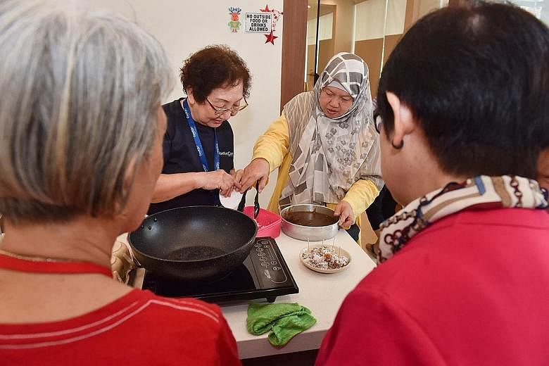 Ms Sally Low, whose chemotherapy treatment causes numbness in her hands, getting a massage from volunteer and freelance therapist Trinia Tjioe at the Yishun centre yesterday. Montfort Care programmes associate Chan Chiew Lan and volunteer Kalsom Abdu