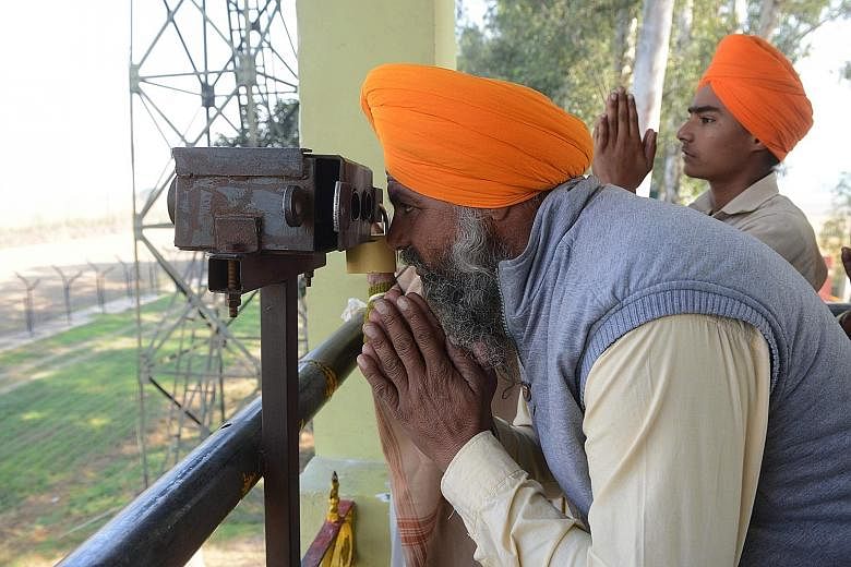 An Indian Sikh devotee looking through a pair of binoculars towards the Gurdwara Darbar Sahib in Kartarpur, Pakistan, from the Indian side at Dera Baba Nanak, on the outskirts of Amritsar, on Sunday.