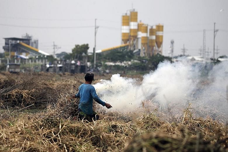 A farmer burning dried grass in Taguig City, south of Manila, yesterday. The UN Environment Programme's report found that the gap between countries' promises in Paris and emissions levels that would be needed to stay consistent with the accord is eve
