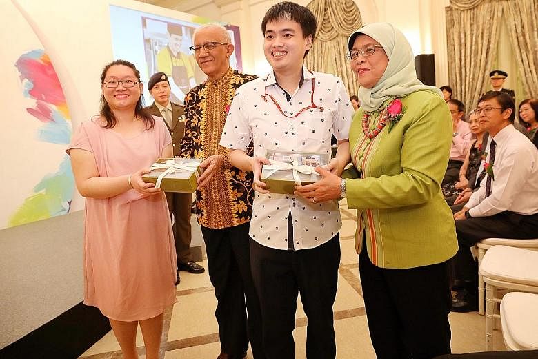 Metta Cafe apprentices Heng Shen, 26, and Shirley Heng, 28, presenting cookies to President Halimah Yacob and her husband, Mr Mohamed Abdullah Alhabshee, at the President's Challenge appreciation night at the Istana yesterday. Metta Welfare Associati