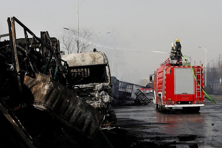 Firefighters work next to burnt vehicles following a blast yesterday near a chemical plant in Zhangjiakou, Hebei province, China. The country's authorities have vowed to improve industrial standards, but environmentalists fear oversight weaknesses st