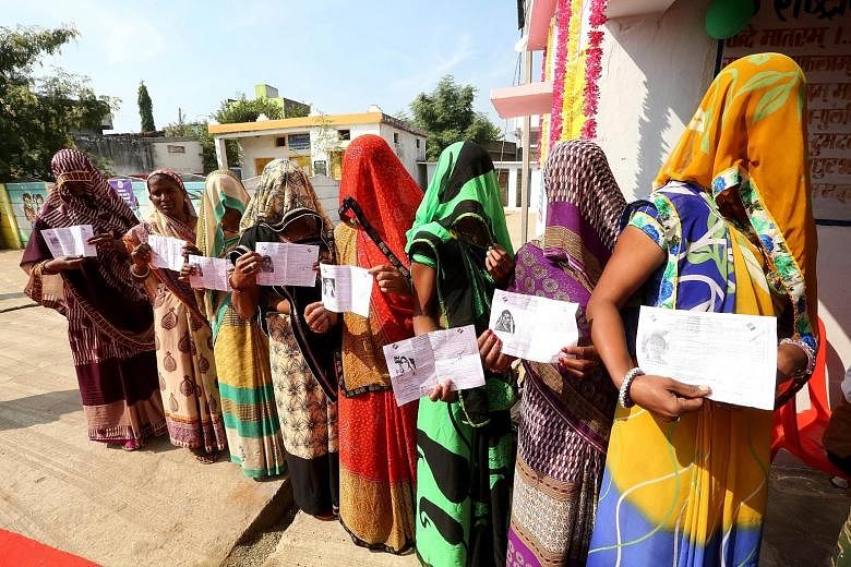 Some women in a village near Bhopal, India, showing their voting slips as they stand in a queue waiting to cast their votes in the Madhya Pradesh state assembly elections, which started on Wednesday. The state is ruled by the Bharatiya Janata Party. 