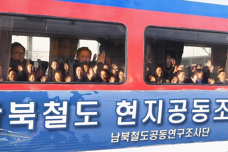 Left: Members of a South Korean delegation waving as they headed to the North for a landmark joint inspection of its railways yesterday. Above: South Korean soldiers opening the gate at the demilitarised zone for the train to pass into the North.