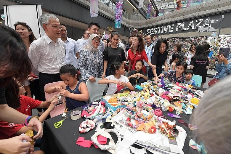 Top: President Halimah Yacob mingling with participants at an art-making session during the launching of the Creative Mindset Hub yesterday at Our Tampines Hub. Above: The President pledging her support to nominate Singapore's hawker culture for Unes