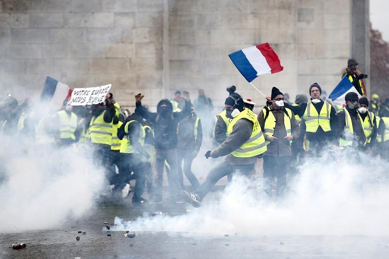 Protesters being sprayed with tear gas by the police on the Champs-Elysees. The avenue was on lockdown, with riot police manning barricades and water cannons. Demonstrators in yellow vests, which have become a symbol of the protest against President 