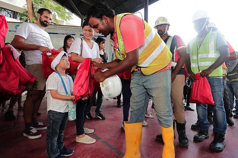 Shen Ruidong, five, and his mother, Madam Khoo Meishan, 35, distributing presents at a Grange Road construction site yesterday. Ms Dipa Swaminathan, ItsRainingRaincoats founder, says she was struck by the care with which the gifts were wrapped.