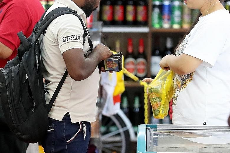 Signs at some liquor stores telling customers of alcohol rules after restricted hours . A store assistant selling a can of beer to a customer at about 9pm on a Sunday (above).
